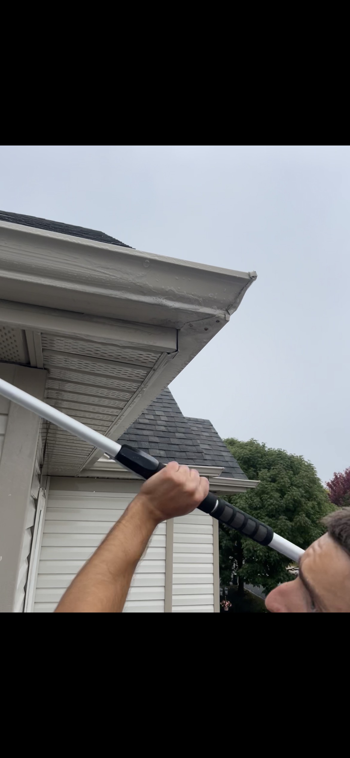 Using extension brush pole to clean eavestrough fascia