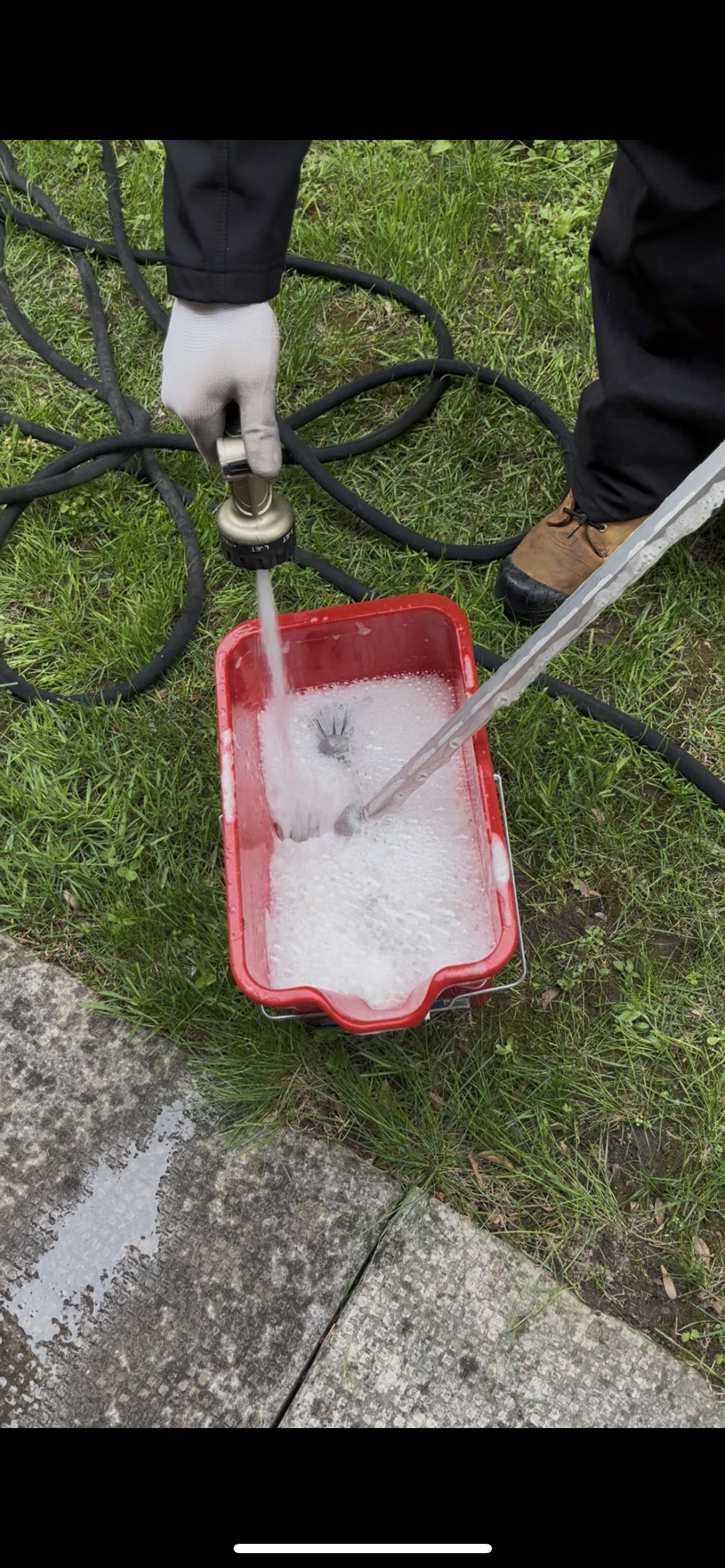 Filling red cleaning bucket with soapy water on lawn